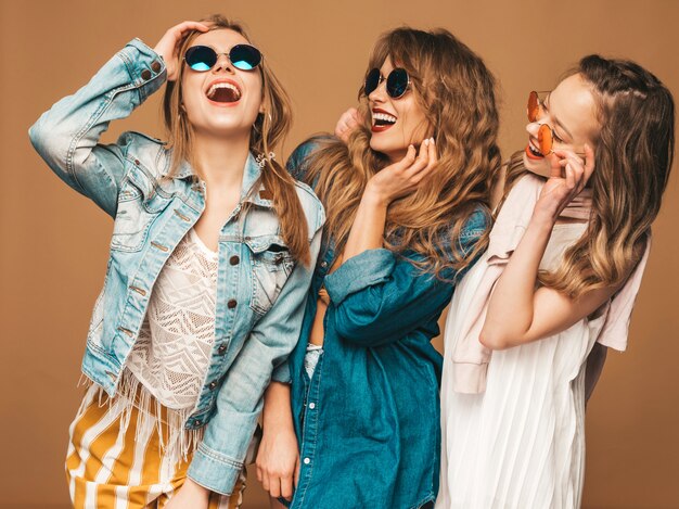 Three young beautiful smiling girls in trendy summer casual jeans clothes. sexy carefree women posing. positive models in sunglasses