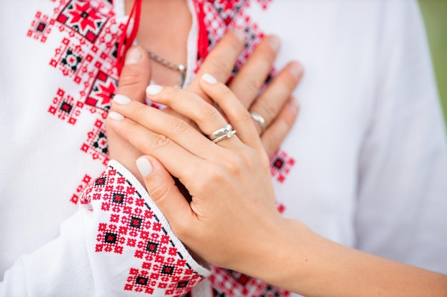 A young ukrainian couple got married and are holding hands together near a vyshyvanka